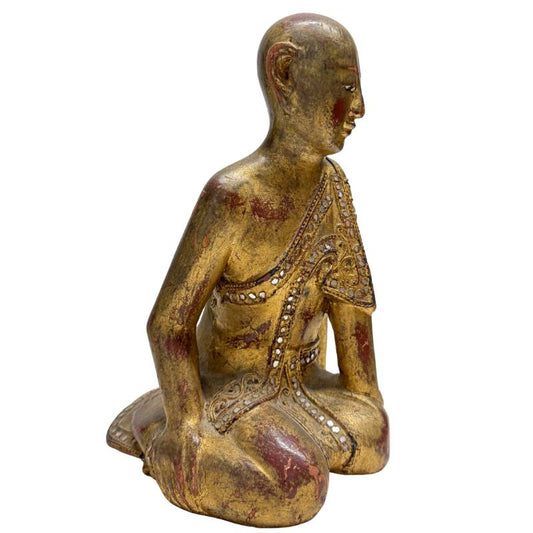 Close-up van authentiek bladgoud en rode laklaag op een antiek houten beeld.