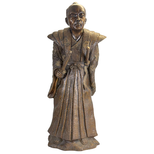 Een historisch Japans bronzen sculptuur van een Samurai uit de Meiji-periode tentoongesteld in een museale opstelling.