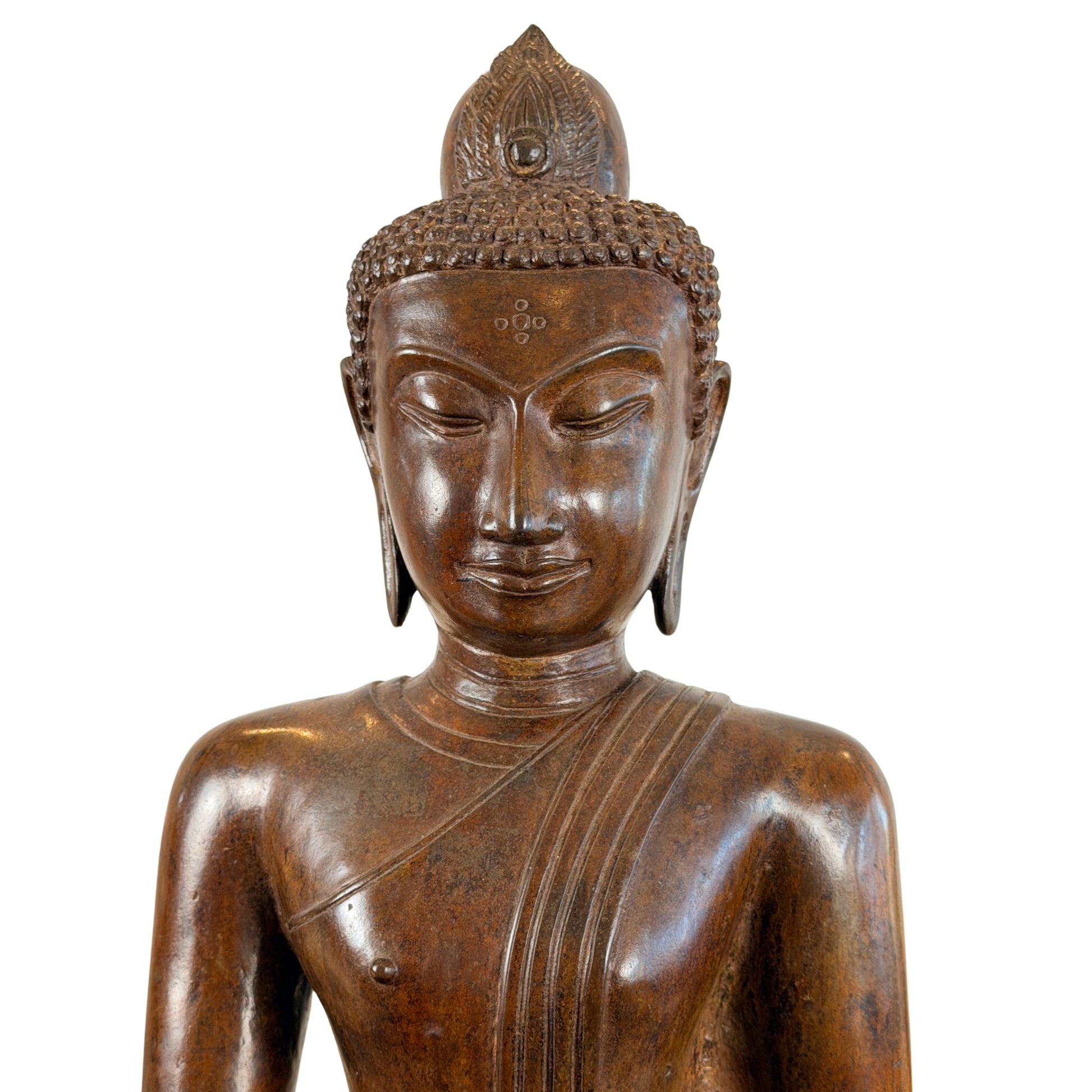Macro-opname van het hoofd en de schouders van een groot antiek Thais bronzen Boeddhabeeld, tonende de verfijnde Sukhothai-stijl gelaatstrekken, lange oorlellen en het kenmerkende stippenpatroon tussen de wenkbrauwen.
