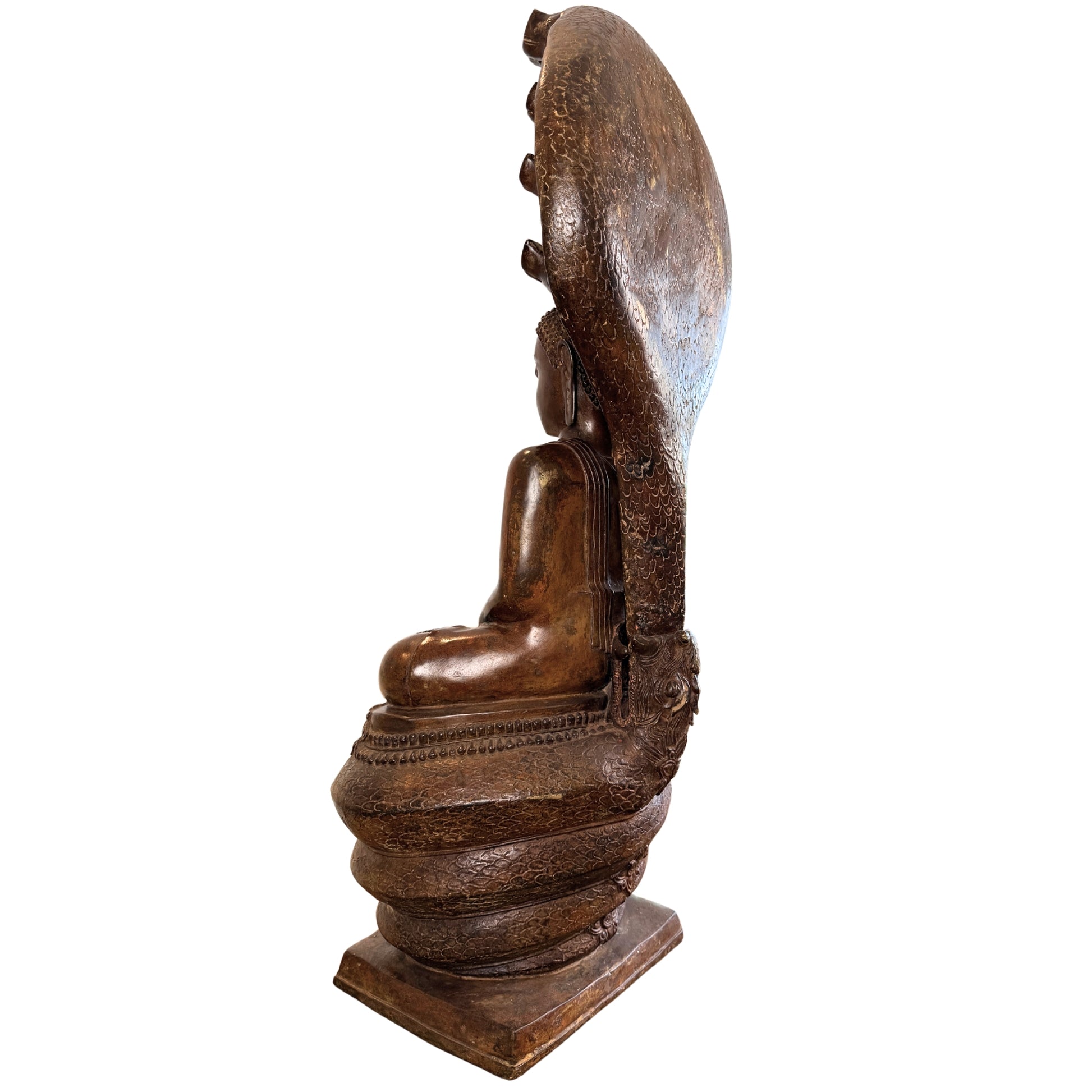 Driekwart achteraanzicht van een groot antiek Thais bronzen Boeddhabeeld onder de koepel van de Naga-slang, met focus op de textuur van de achterkant van het slangenscherm en de gelaagde patina