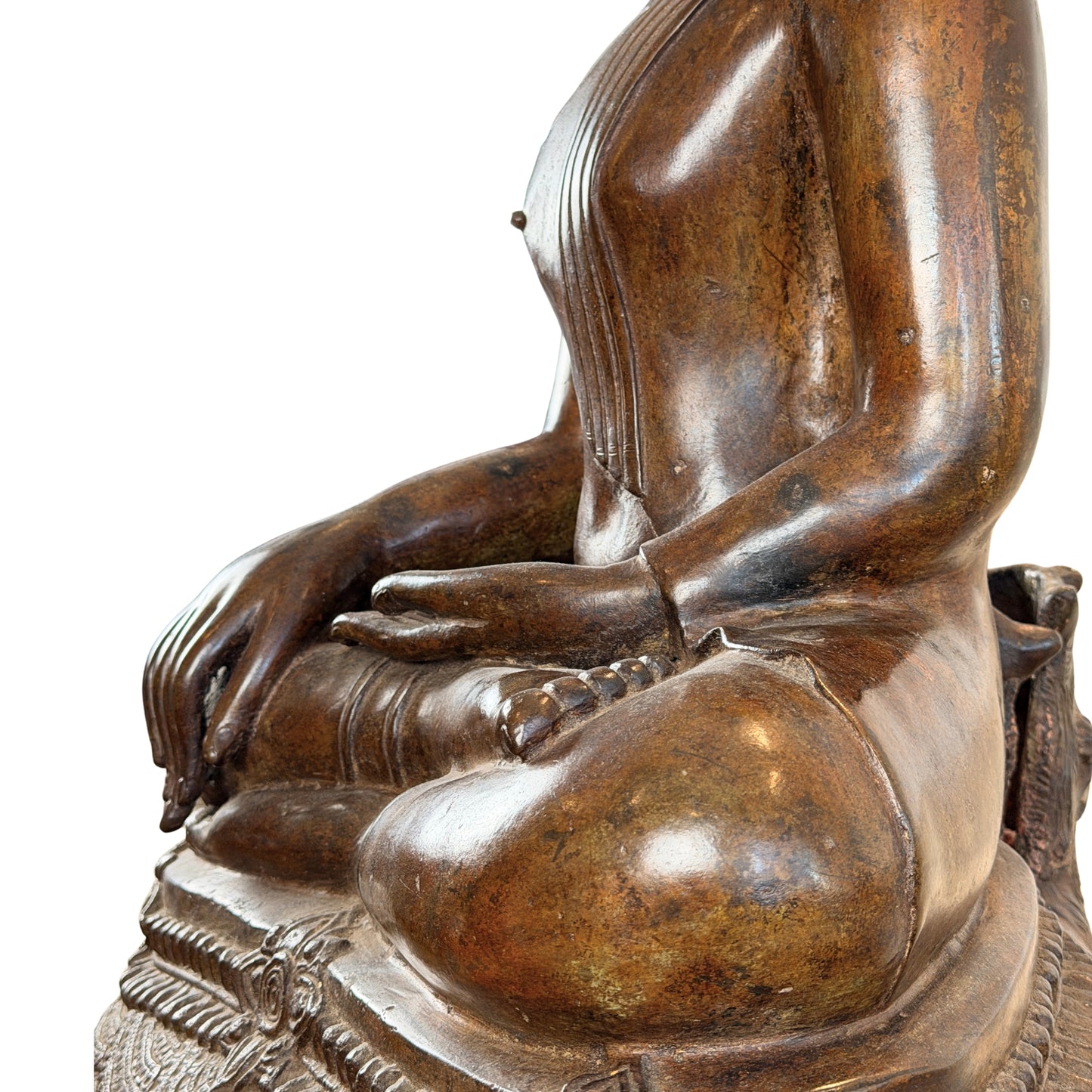 Close-up van de zijkant van een groot antiek Thais bronzen Boeddhabeeld, met de nadruk op de elegante anatomie van de arm, de handhouding en de gelaagde patina op de knie