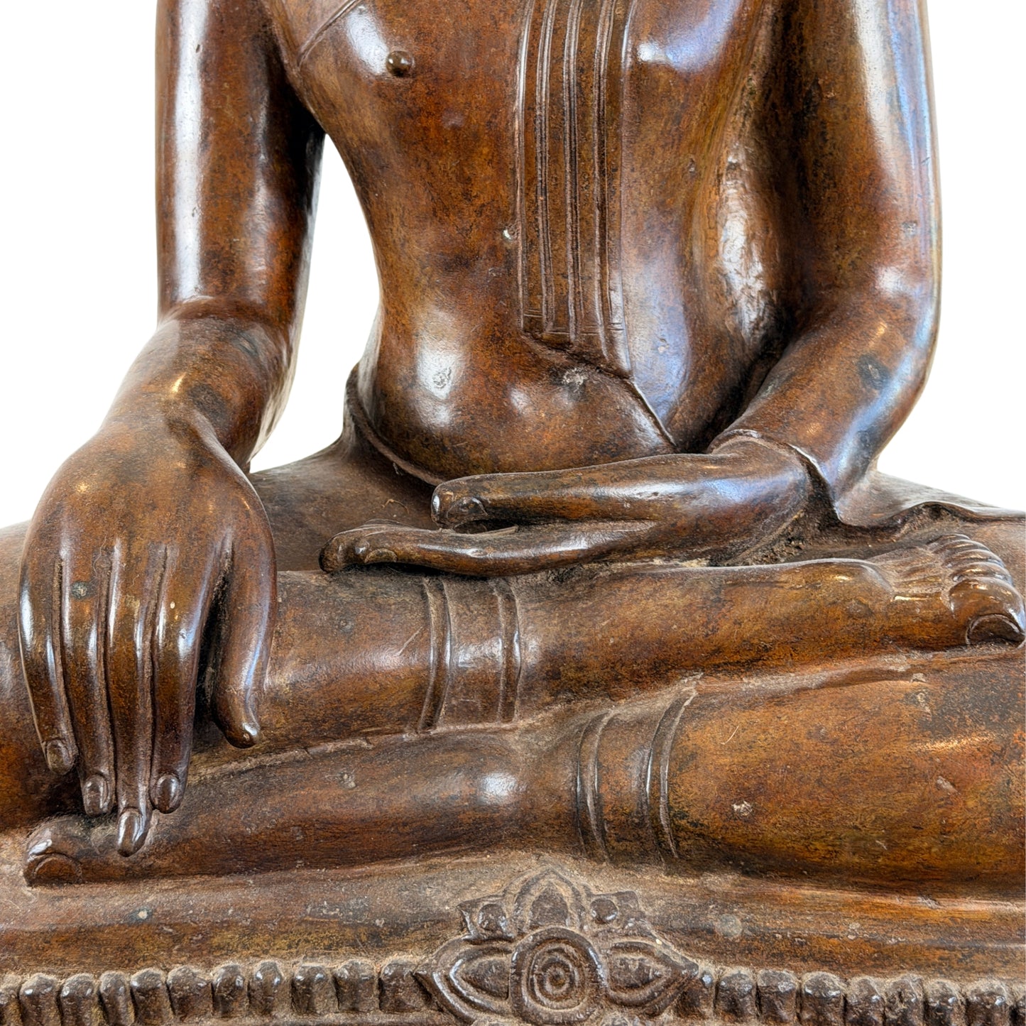 Close-up van de handen en benen van een zittend antiek Thais bronzen Boeddhabeeld, met de kenmerkende vingers in het aarde-aanrakende gebaar en een decoratief bloemmotief centraal op de troonbasis.