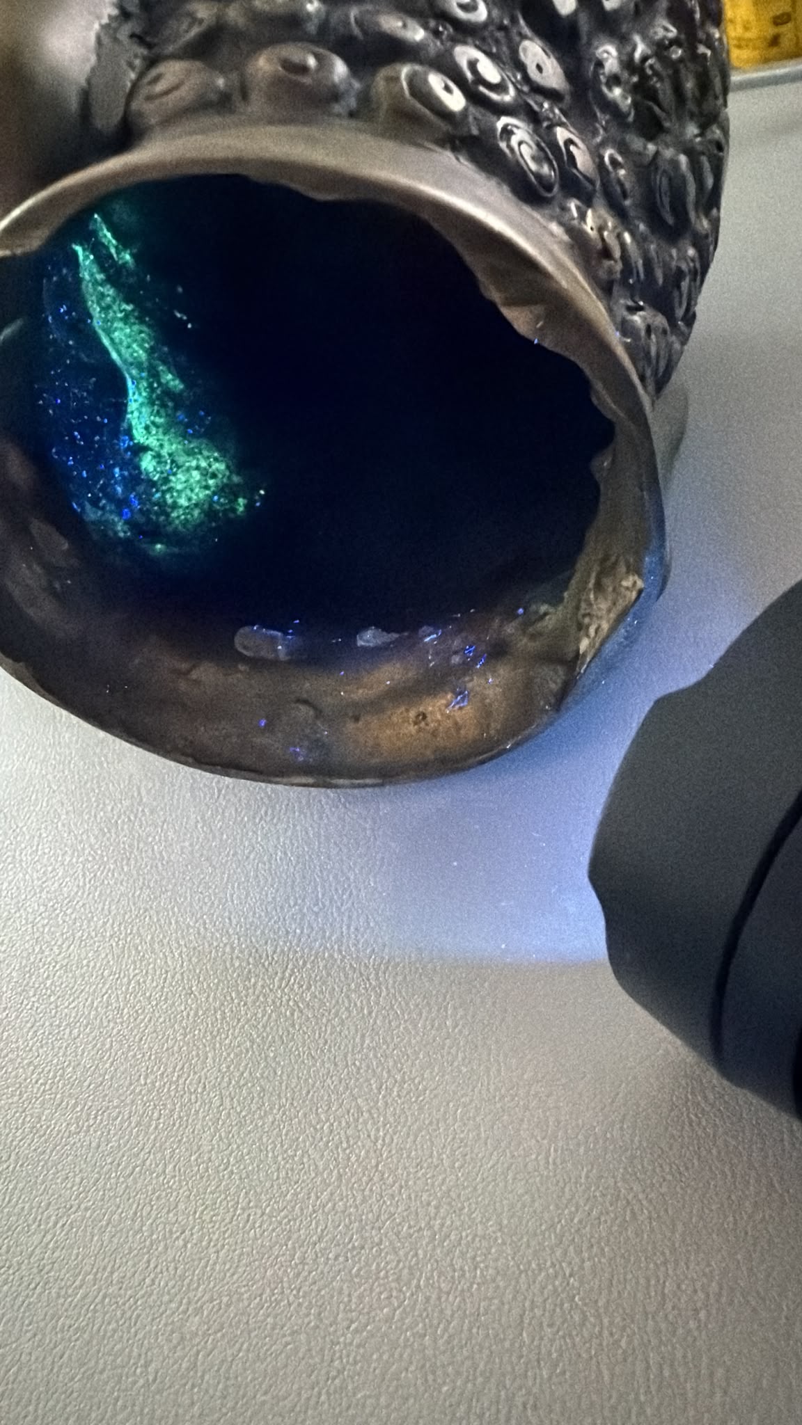 UV-opname van een antiek Thais bronzen Boeddhahoofd met interne fluorescentie en oude patina.