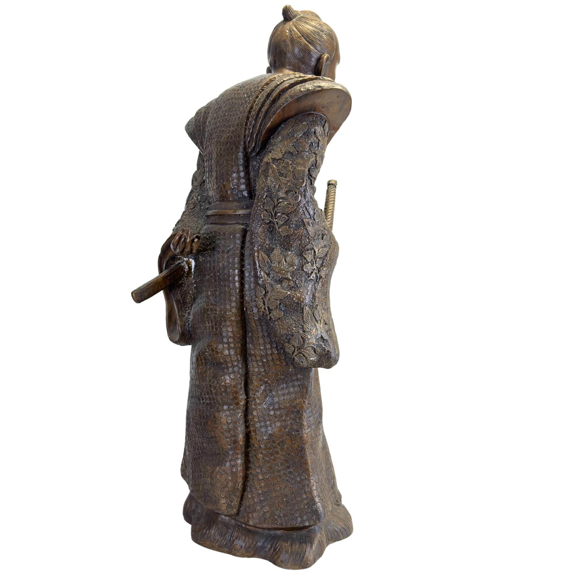 Schuine achterzijde van het bronzen Meiji beeld tonend het florale hoogreliëf op de mouwen en de vloeiende plooien.