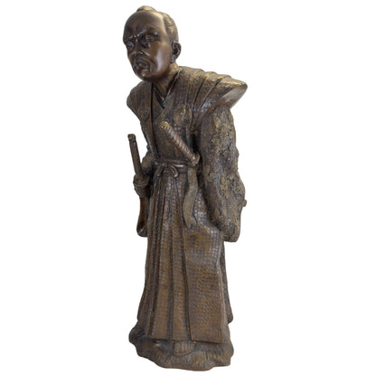 Driekwart vooraanzicht van de bronzen Samurai in zijn ceremoniële krijgshouding met de Daisho-zwaarden prominent zichtbaar.