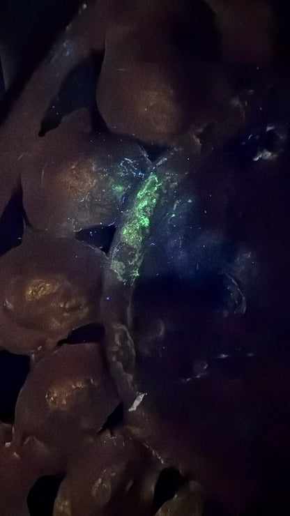 UV-foto van een antieke Groene Tara uit Nepal met zichtbare fluorescentie, vuurvergulding, oude restauraties en natuurlijke patina onder ultraviolet licht.
