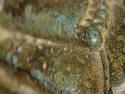 Microscoopdetail van gewaad en borst met groenblauwe koperpatina en natuurlijke slijtage