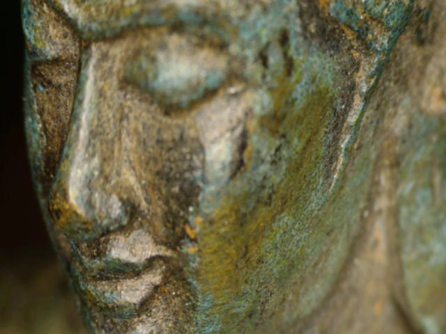 Microscoopdetail van het gezicht met patina en minuscule resten van een oudere vergulde afwerking