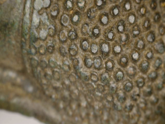 Microscoopdetail van haarkrullen en natuurlijke slijtage op antieke Thaise bronzen Boeddha