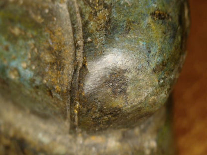 Microscoopdetail van afgesleten knieoppervlak en omringende oude patina op de Thaise Boeddha