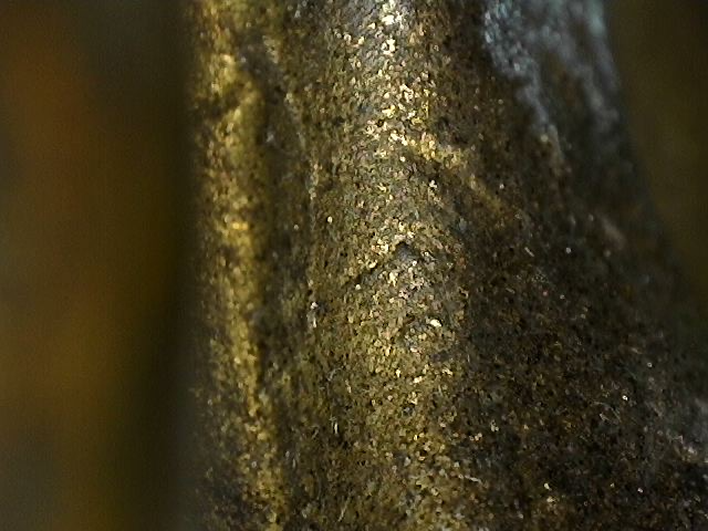 Microscopisch detail van oxidatie met cuprit en malachiet op bronzen Boeddhabeeld