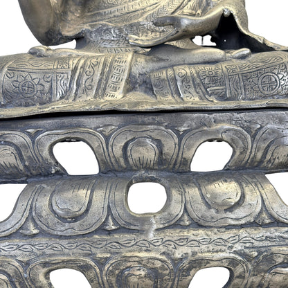 Detail van de opengewerkte lotusbasis met brede bloembladen onder de gekruiste benen van de Boeddha.