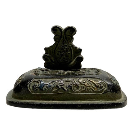 Detailopname van het losse bronzen deksel met wolkenreliëf, sporen van goud en een centrale knop in de vorm van een lotusjuweel.