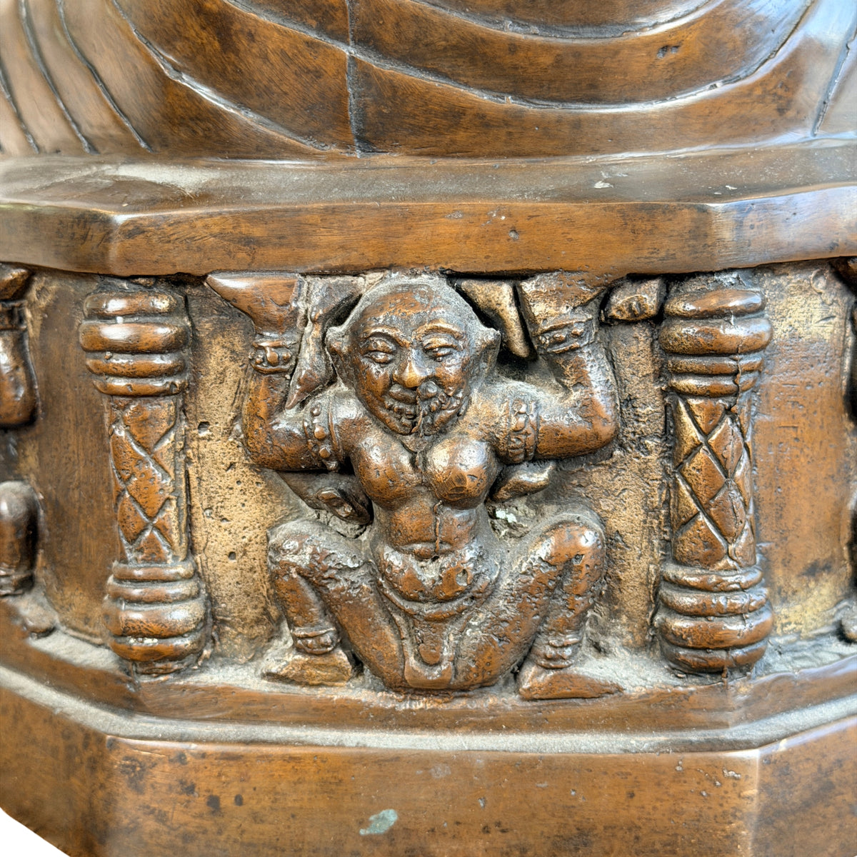 Gehurkte atlant (yaksha) die de troon draagt, tussen zuiltjes, detail