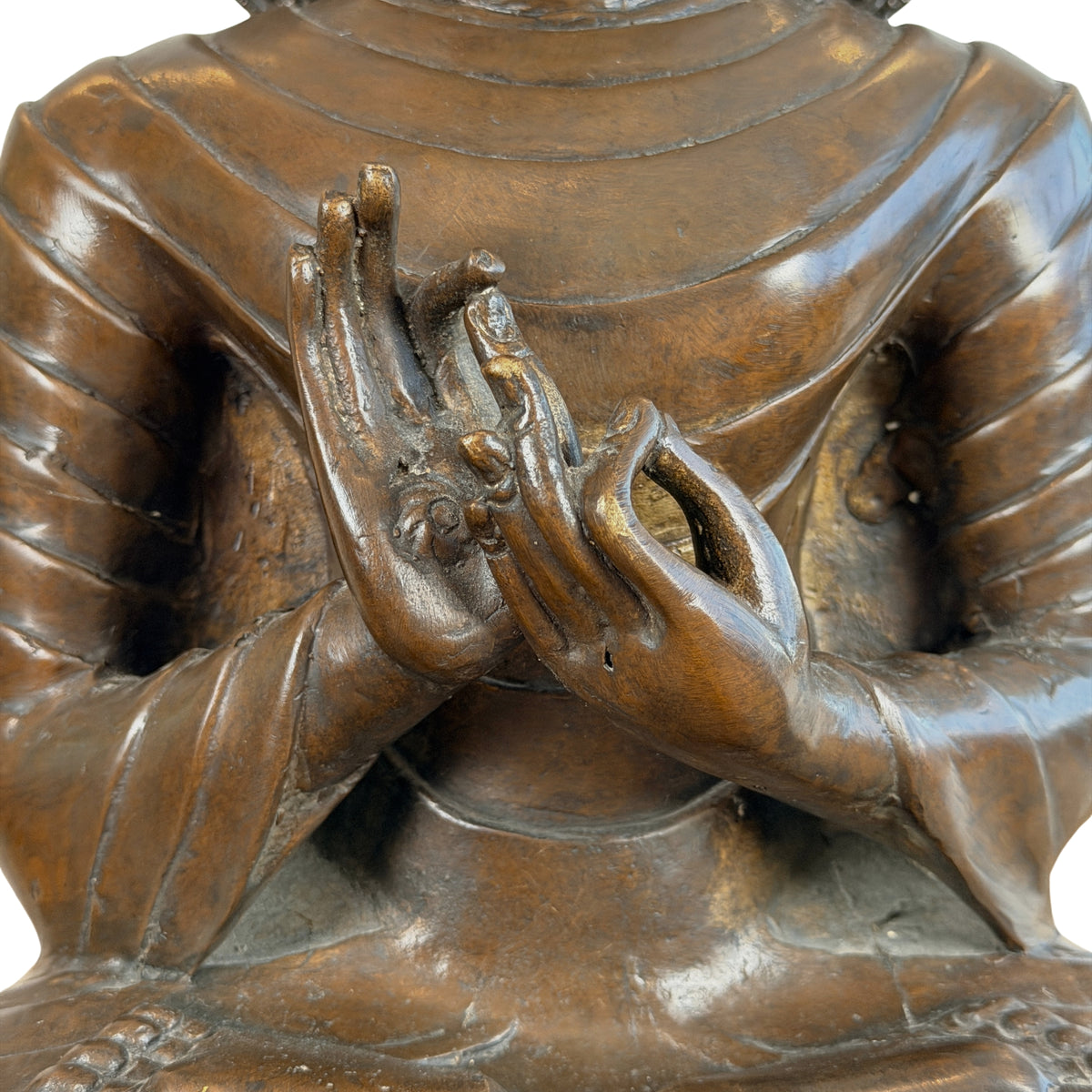 Handen voor de borst in dharmachakra mudra met geribde gewaadplooien, close-up