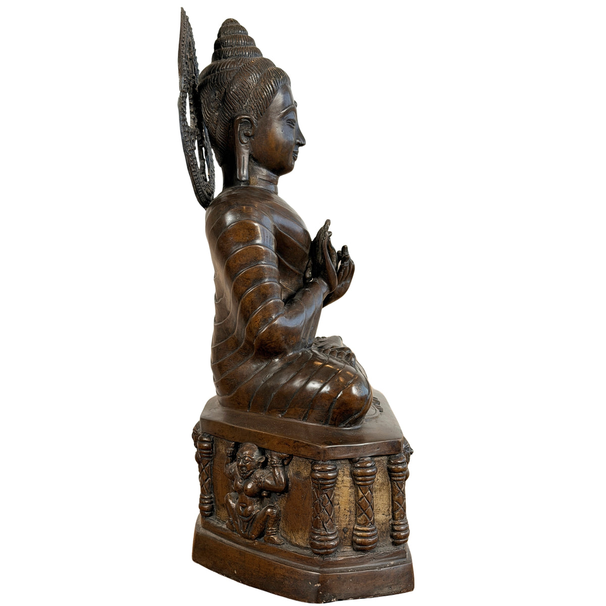 Zijaanzicht van de zittende bronzen Boeddha met stralenkrans op troon