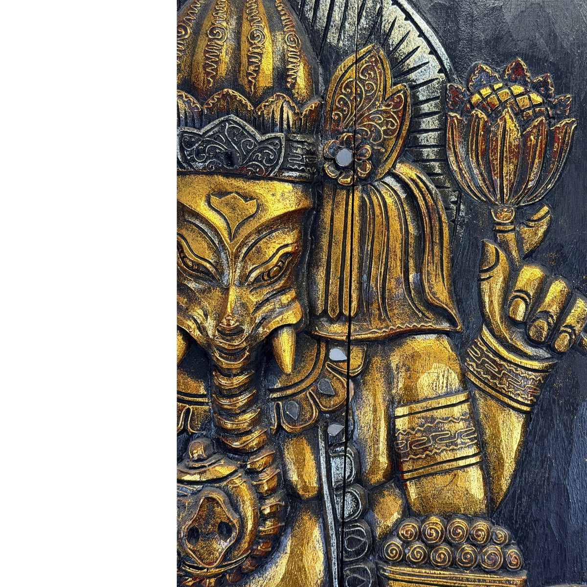 Detail van Ganesha met een lotus in de bovenste linkerhand, een schaal daaronder en goudkleurige decoratie.