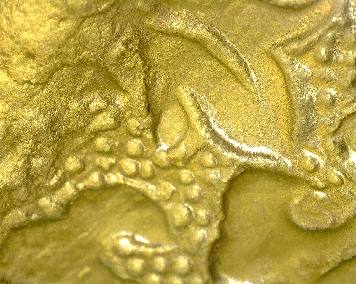 Microscopische opname van fijn gegraveerde lotusdecoratie met resten van originele vuurvergulding.