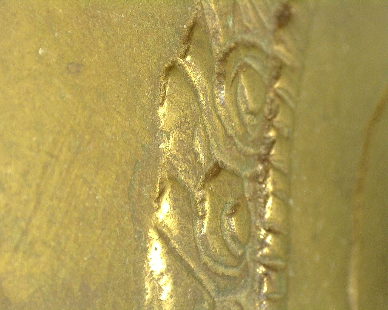 Microscopische opname van de originele vuurvergulding met natuurlijke slijtage en historische oppervlaktestructuur.