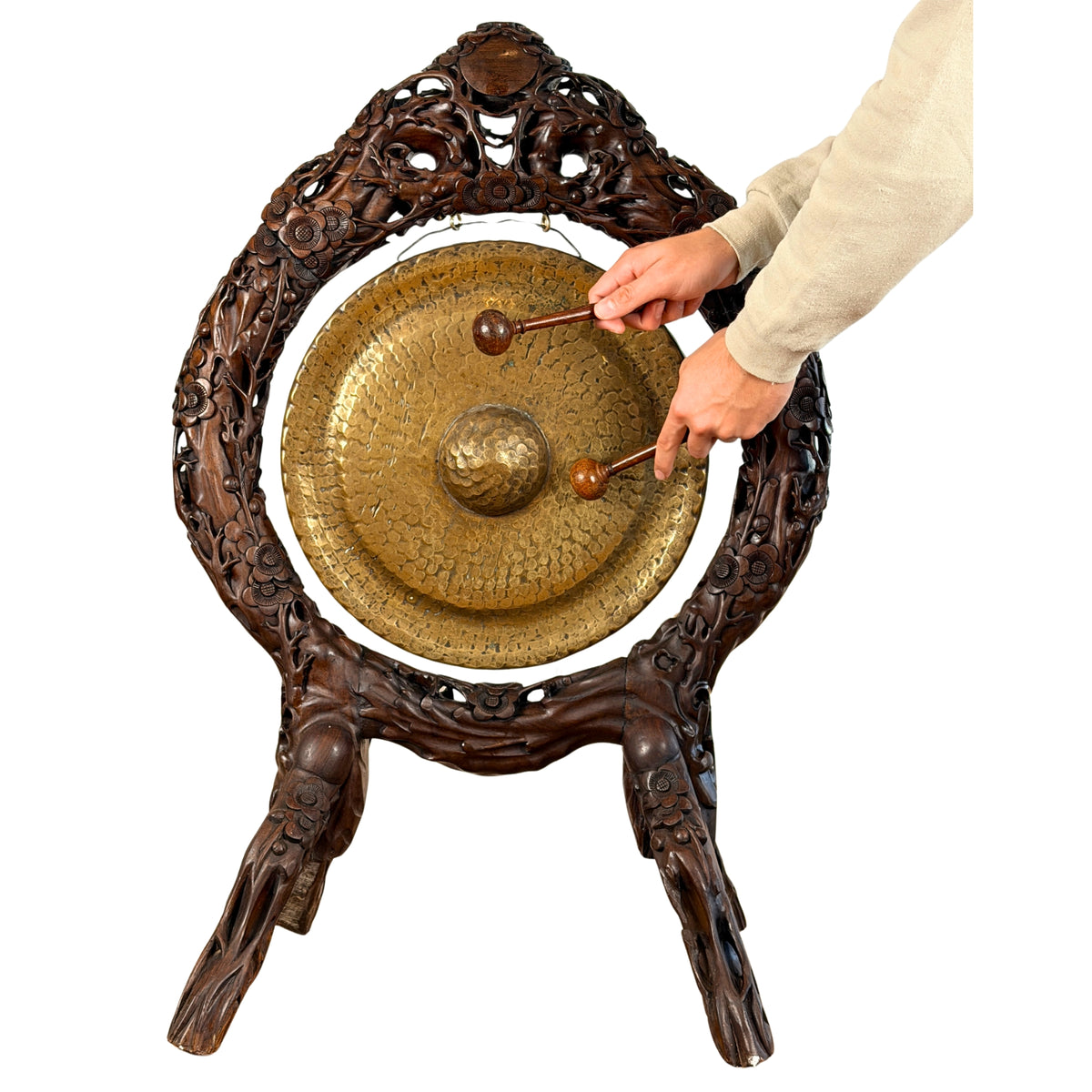 Gong in de gesneden standaard met de twee houten slagstokken in de hand