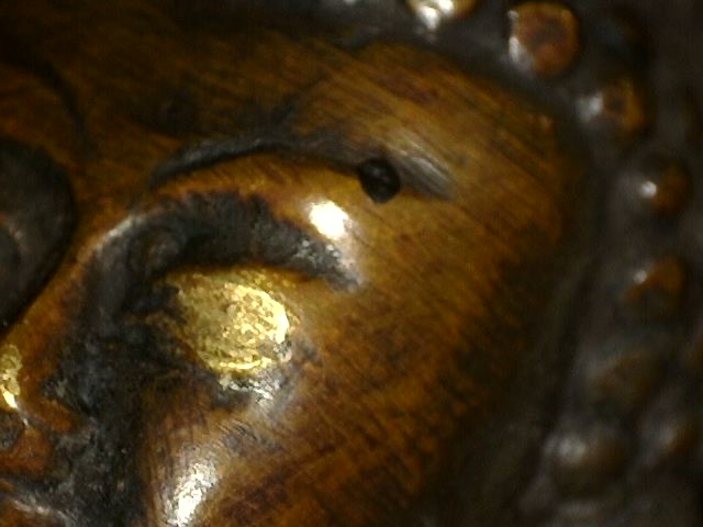 Microscoop close-up van oude vuurvergulding op bronzen Boeddha met dhyana mudra