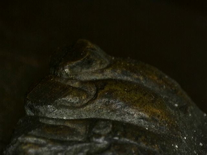 Microscoopdetail van diepe patina-opbouw op antiek Thais bronzen kunstwerk