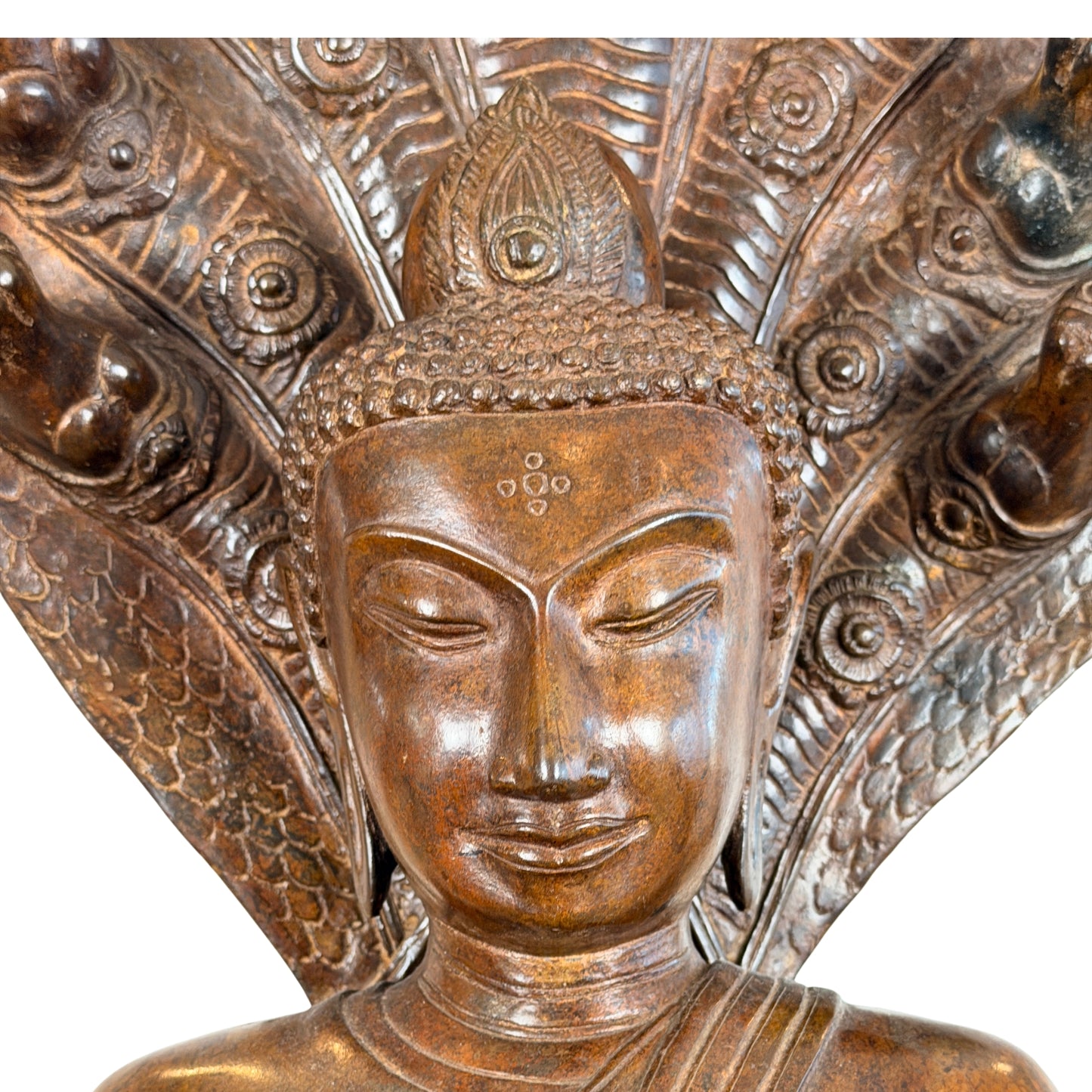 Vooraanzicht van een monumentaal bronzen Phra Nagprok Boeddhabeeld in Grahi-stijl, zittend onder een zevenkoppige Naga-slangenkap met een geponst vijfvoudig cirkelpatroon als urna op het voorhoofd.