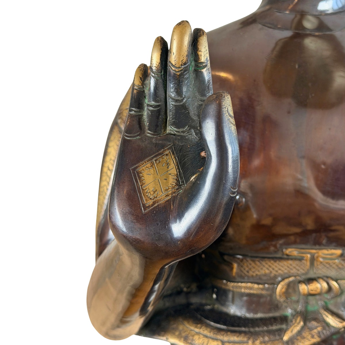 Opgeheven rechterhand in abhaya mudra met vergulde handpalmmarkering en gordel