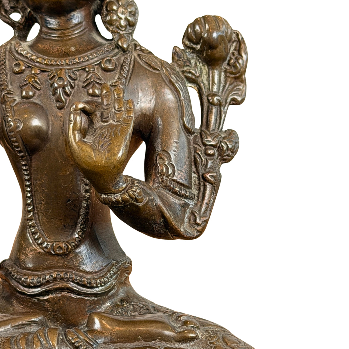 Linkerzijde: opgeheven hand in vitarka mudra en de utpala-lotus langs de schouder