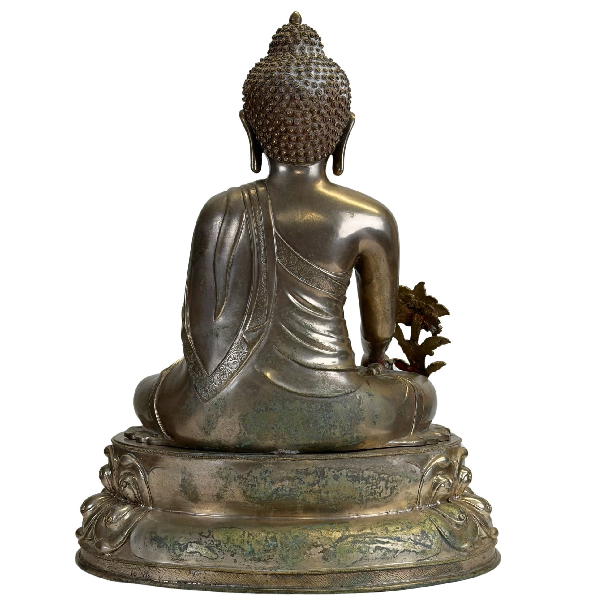 Achterzijde van een antieke Newar Bhaisajyaguru in verzilverd brons op een tweedelige lotustroon, met natuurlijke patina, slijtage en fijn gegraveerde monnikspij aan de rug.