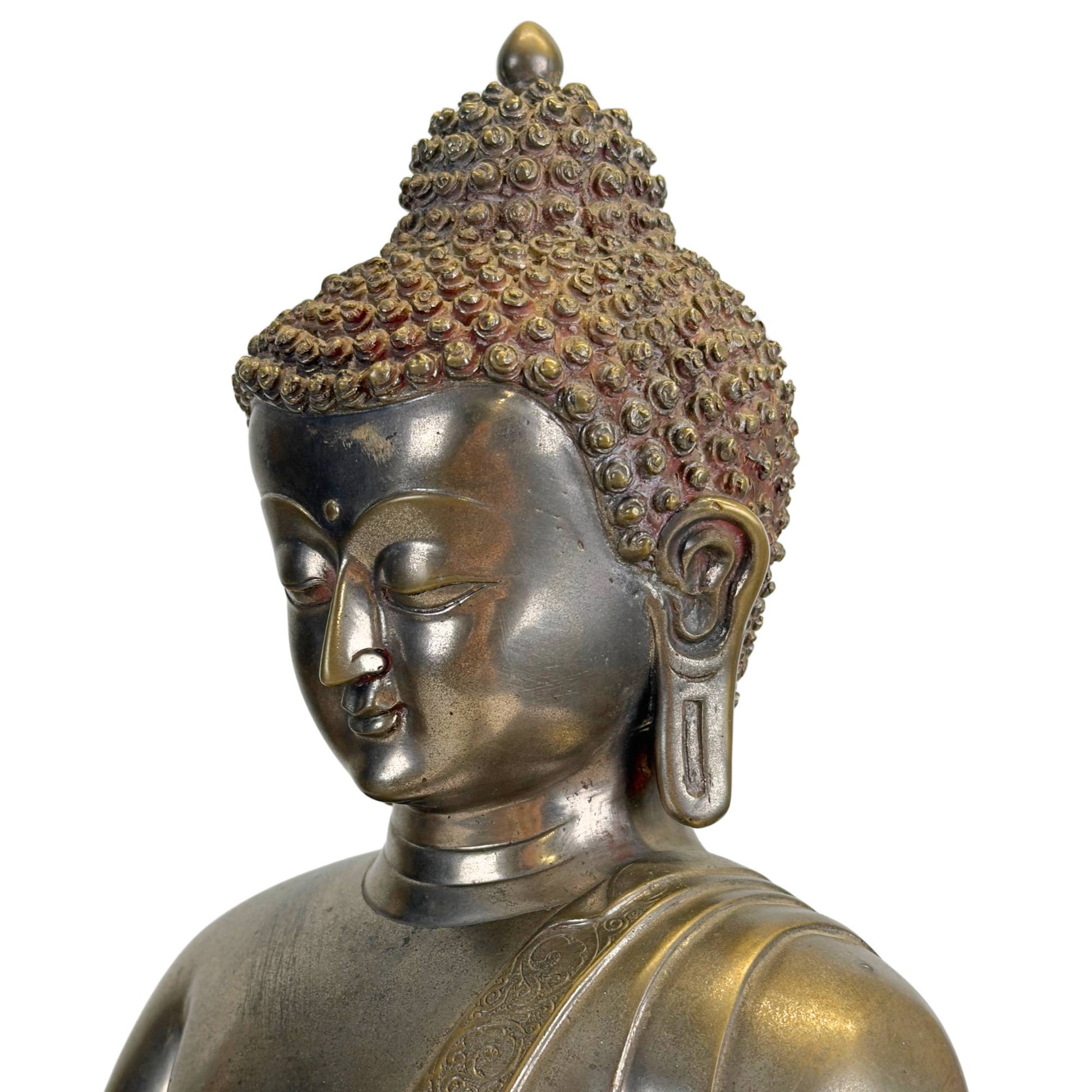 Schuin detail van het gezicht van een antieke Newar Bhaisajyaguru in verzilverd brons met verfijnde amandelvormige ogen, zachte lippen, lange oorlellen, karakteristieke haarkrullen en natuurlijke slijtage passend bij een 14e–15e-eeuws beeld.