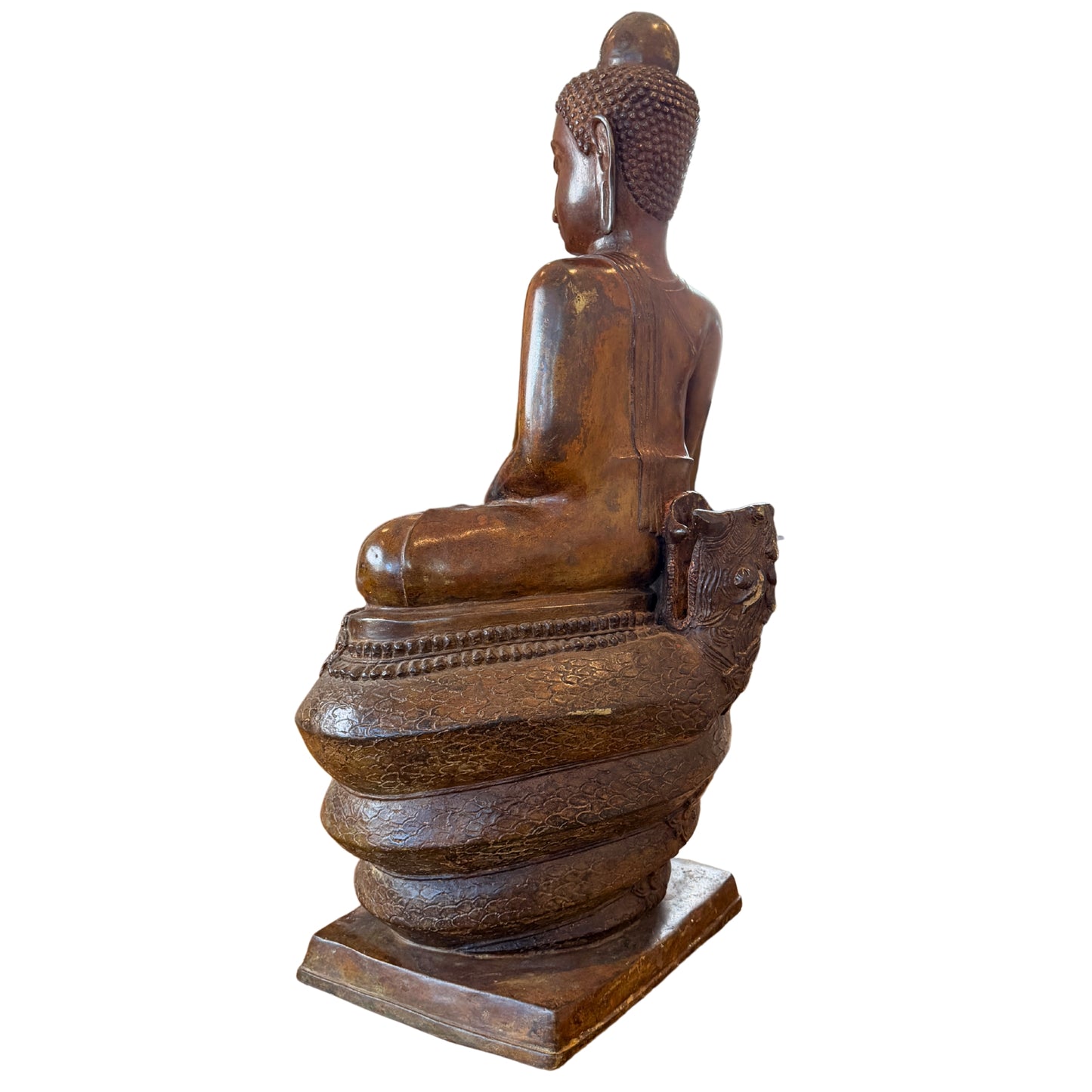 Schuin achteraanzicht van een monumentaal bronzen Boeddhabeeld van 122 cm hoog op de opgerolde naga-windingen, gefotografeerd zonder de afneembare kap waarbij de open penverbinding aan de achterzijde van de troon zichtbaar is