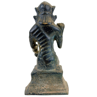 Achteraanzicht van de Thaise bronzen Nang Kwak op haar gedecoreerde sokkel.