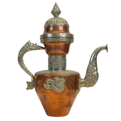 Vooraanzicht van de vintage Himalayische koperen drakenkan met zilverkleurige paktong repoussé applicaties en een drakenmotief op de buik.
