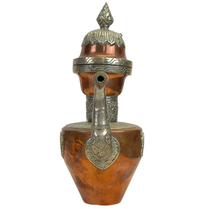 Direct vooraanzicht van de schenktuit met de florale en mythologische paktong reliëfelementen aan de basis van de tuit.