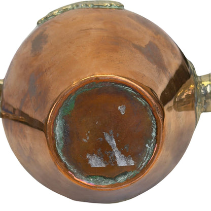 Direct onderaanzicht van de theepot, tonend de messing standring met groene verdigris-buildup en witte papierlijmresten in het centrum.