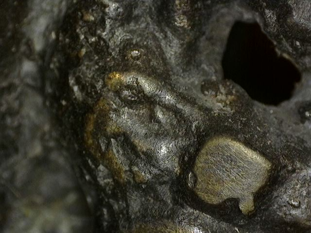 Microscopisch detail van afgeronde slijtage van vuurvergulding op historisch Vishnu borstbeeld