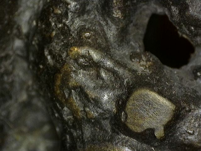 Microscopisch detail van afgeronde slijtage van vuurvergulding op historisch Vishnu borstbeeld