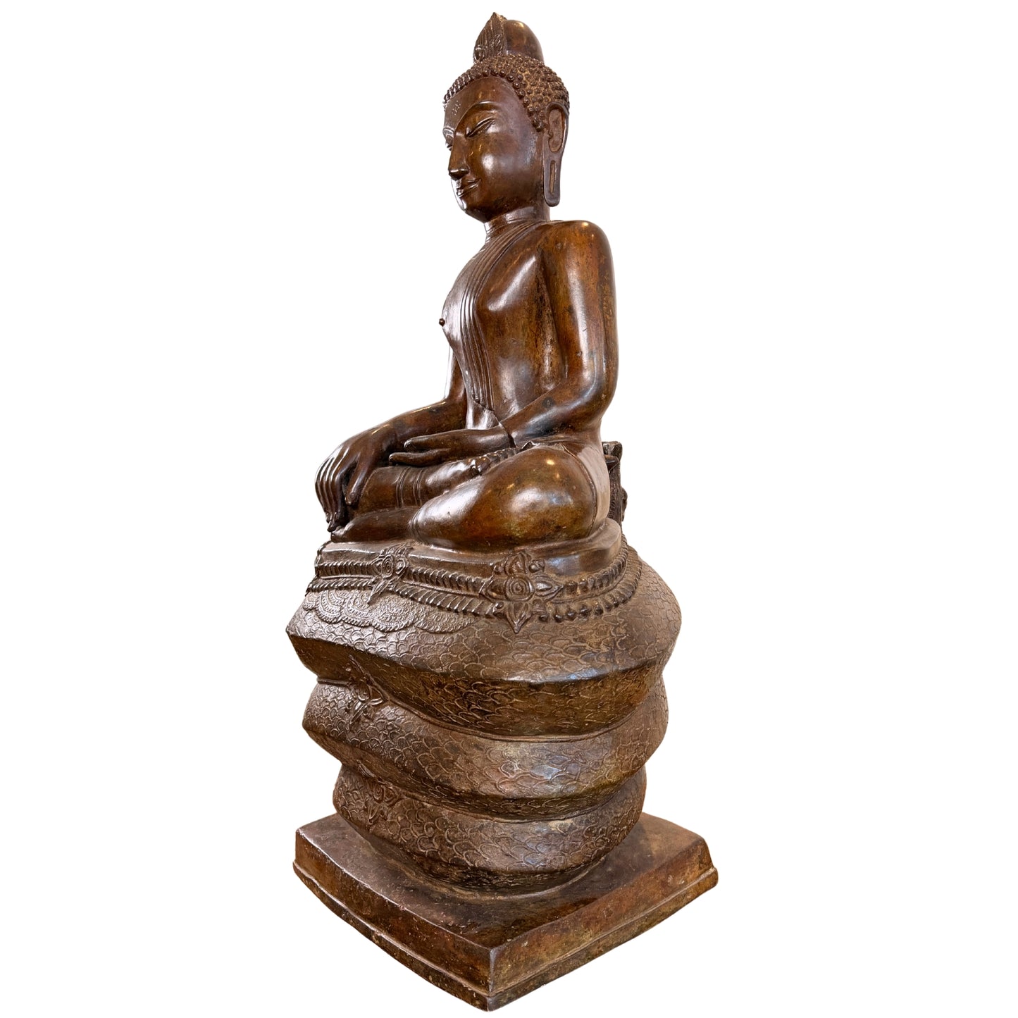 Zijaanzicht in profiel van een monumentaal bronzen Boeddhabeeld van 122 cm hoog, zittend op de drie opgerolde lussen van de Naga-slang, gefotografeerd zonder het afneembare slangenscherm.