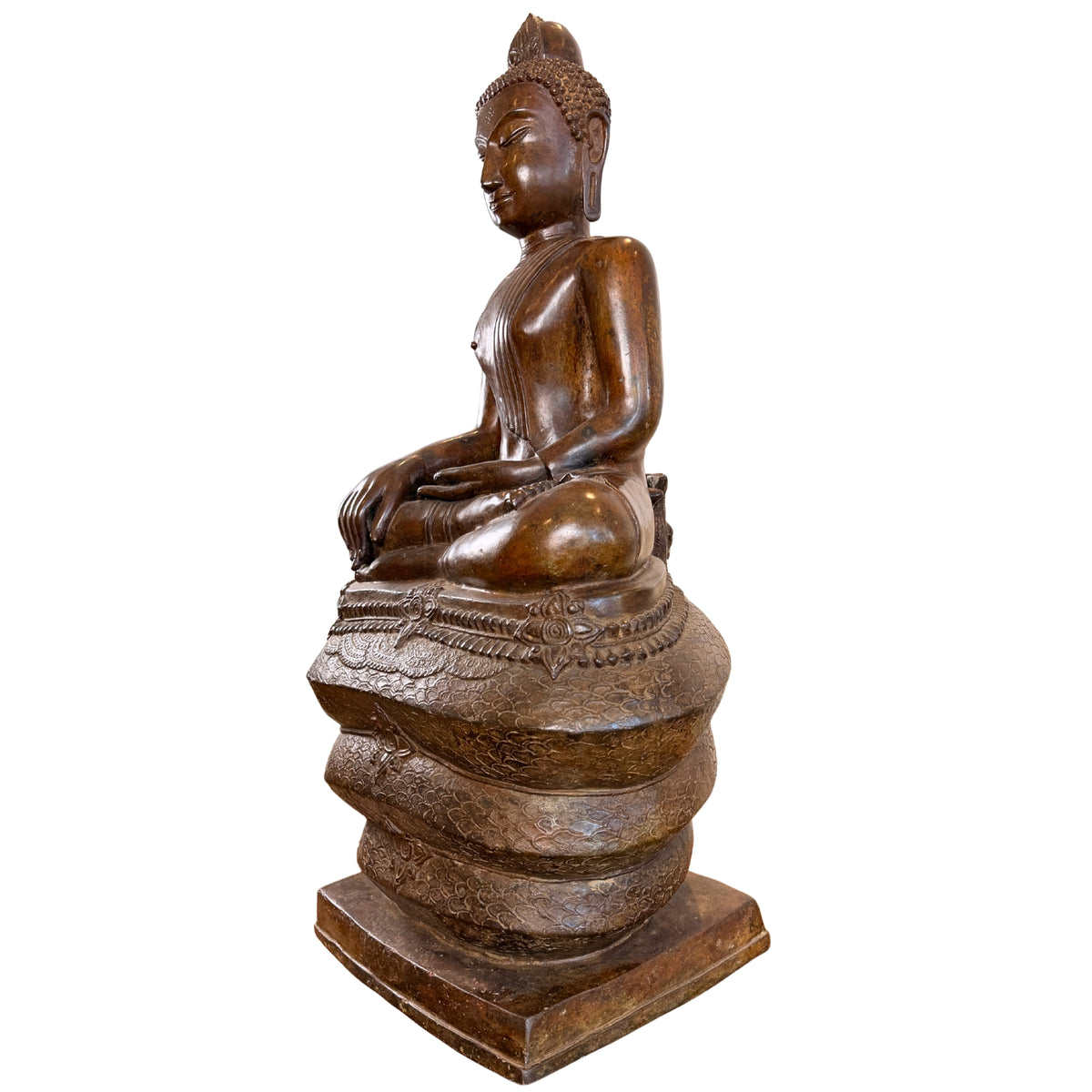 Zijaanzicht in profiel van een monumentaal bronzen Boeddhabeeld van 122 cm hoog, zittend op de drie opgerolde lussen van de Naga-slang, gefotografeerd zonder het afneembare slangenscherm.