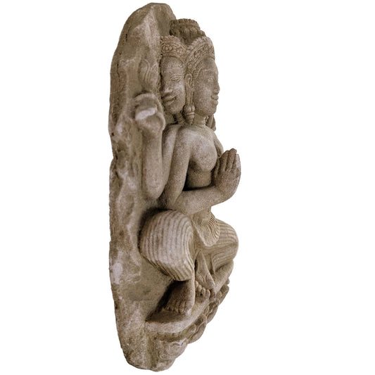 Zijaanzicht van een zandstenen beeld met drie gezichten en gedetailleerd kroonwerk.
