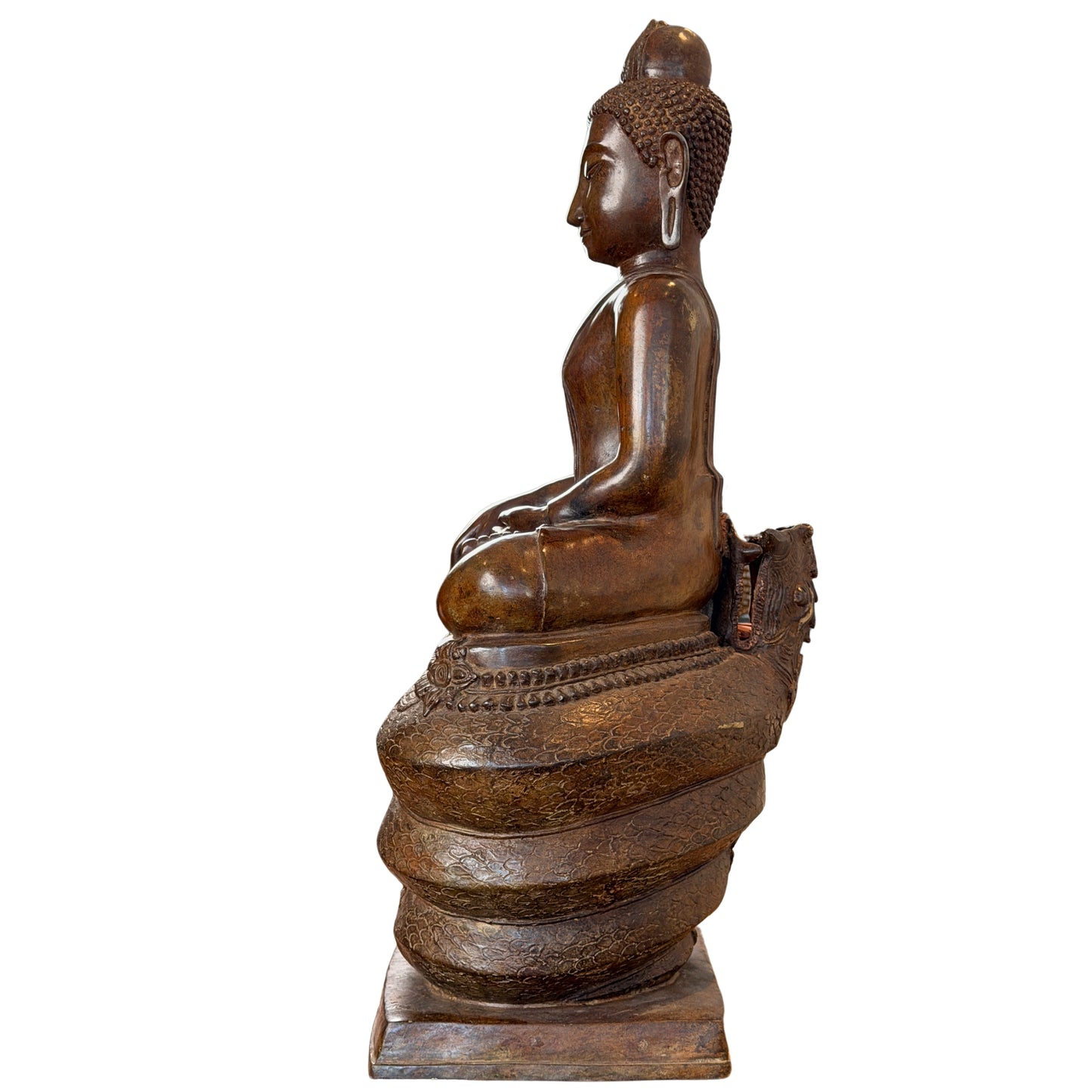 Volledig en strak profielaanzicht van de zijkant van een groot antiek Thais bronzen Boeddhabeeld op een bewerkte naga-troon, tonende de kaarsrechte rughouding en de gelaatstrekken van de zijkant